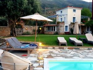 a pool with an umbrella and chairs and a house at Private Swimmingpool in Cottage in Poros