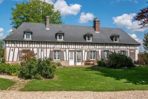 una casa vieja con un patio verde delante de ella en Cottage 4 chambres avec cheminée, en Épégard