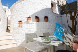 un mur en briques blanches avec une table et des chaises dans l'établissement Le Alcove - Luxury Hotel nei Trulli, à Alberobello
