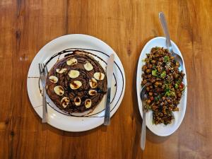two plates of food on a wooden table at La Heim Hostels in Manāli +56 photos