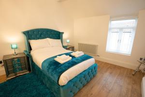 a bedroom with a blue bed with two towels on it at Cottage Buttercup Yarm in Stockton-on-Tees