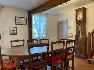 une salle à manger avec une table, des chaises et une horloge dans l'établissement Cottage 4 chambres avec cheminée, à Épégard