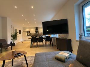 sala de estar con TV de pantalla plana grande en la pared en Luxuriöses 65 qm Apartment »B28« für 2+2 Gäste, en Chemnitz