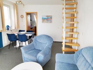 a living room with a blue chair and a staircase at Skipper in Dorum-Neufeld