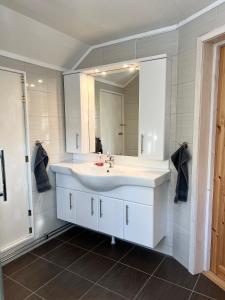 a bathroom with a white sink and a mirror at Mysigt fritidshus och annex med eget sjöläge! in Torsby