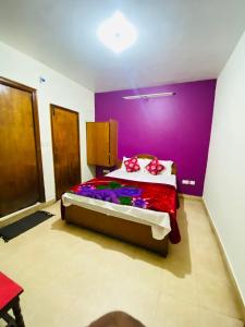 een slaapkamer met een bed met een paarse muur bij Hotel Nakshatra in Ooty