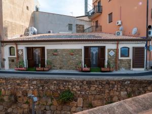 un edificio al lado de una pared de piedra en Sicilia Bedda - B&B - Rooms - Apartments, en Santo Stefano di Camastra