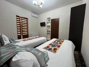 a hotel room with two beds and a window at OLD SAFARI HOTEL make yourself at home in Bukhara