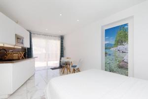 a white bedroom with a bed and a kitchen at Studio tout confort avec parking et terrasse à Eze village in Éze
