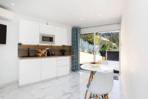 uma cozinha com armários brancos e uma mesa e cadeiras em Studio tout confort avec parking et terrasse à Eze village em Èze