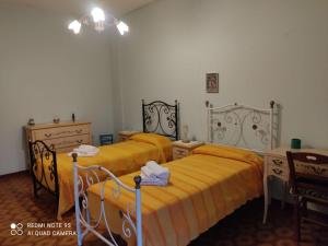 two beds in a bedroom with yellow sheets and a table at CasAda spazioso e luminoso appartamento in Tricase +21 photos