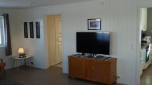 un salon avec une télévision à écran plat sur une armoire dans l'établissement Heggelund, à Svensby