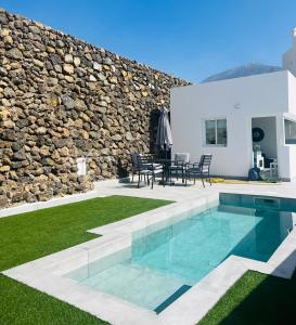 einen Hinterhof mit einem Pool und einer Steinmauer in der Unterkunft Mireya home in Icod de los Vinos