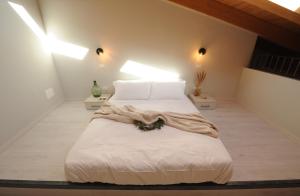 um quarto com uma cama grande com lençóis brancos e almofadas em Bene39 em Turim