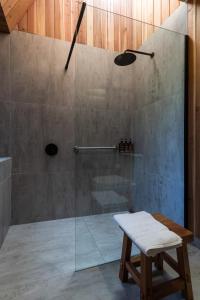a shower with a glass door and a bench in a bathroom at Tawa Refugio del Puelo in Puelo