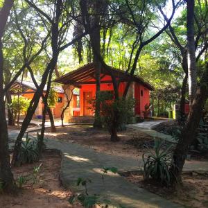 a small red house with a pathway and trees at Granja Mi Retiro in Areguá