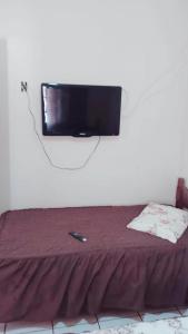 a flat screen tv hanging on a wall above a bed at Hotel Casa Grande Max in Marília