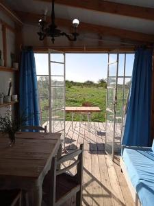 Habitación con mesa, cortinas azules y mesa. en Uy MÁGICA Cabaña en entorno Natural único, en Mercedes
