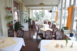 a dining room with tables and chairs and windows at Hotel Poseidon in Kühlungsborn