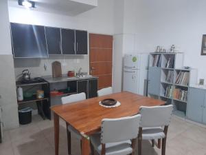 a kitchen with a wooden table and white chairs at departamento centrico de un dormitorio para tres personas in San Juan