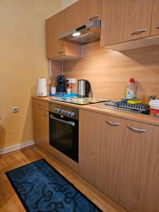 Una cocina con gabinetes de madera y un horno de estufa. en Eigener Eingang, 1-Zimmer mit Bett und große Wohnküche mit Schlafcouch, en Oberhausen 5 fotos más