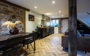 cocina con mesa, sillas y pared de piedra en Gardener's Cottage, en Chepstow