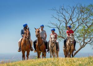 grupa ludzi jeżdżących konno na polu w obiekcie Buena Vista del Rincón Eco Adventure Park Hotel & Spa w mieście Liberia