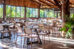 un comedor con mesas, sillas y ventanas en Buena Vista del Rincón Eco Adventure Park Hotel & Spa, en Liberia