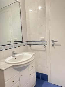 La salle de bains blanche est pourvue d'un lavabo et d'un miroir. dans l'établissement IL FARO in centro vicino Pompei Amalfi Sorrento, à Castellammare di Stabia
