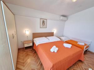 トゥチェピにあるApartmani Dalijaのオレンジのシーツとタオルが備わる客室内のベッド2台