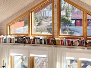 uma fila de livros numa prateleira em frente às janelas em Holiday home HAMMARÖ em Hammarö