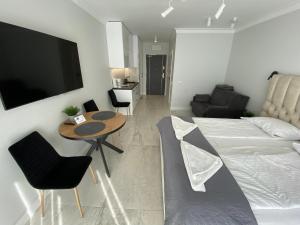 uma sala de estar com uma cama, uma mesa e cadeiras em ApartPark Albus1 em Świnoujście
