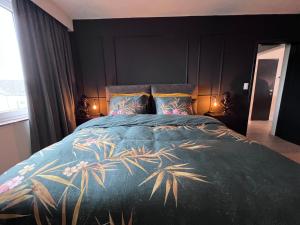 a bedroom with a large bed with a blue bedspread with palm trees at Red cross street in Lommel