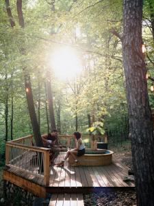 dos personas sentadas en una terraza de madera en el bosque en Kabinka Mátra en Pásztó