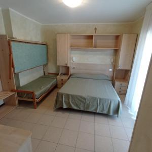 ein kleines Schlafzimmer mit einem Bett und einem Stuhl in der Unterkunft Hotel Arlecchino in Milano Marittima