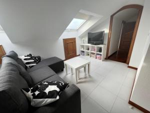 a living room with a couch and a tv at ATICO muy luminoso e increíbles vistas in Baiona