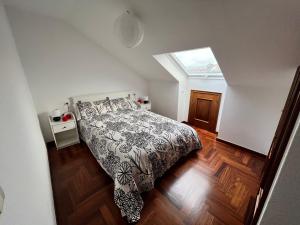 1 dormitorio con 1 cama con edredón blanco y negro en ATICO muy luminoso e increíbles vistas en Baiona