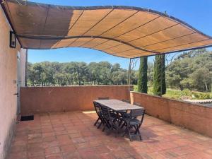 patio ze stołem i krzesłami pod baldachimem w obiekcie Appartement unique dans le domaine de la sangliere w mieście Bormes-les-Mimosas