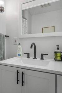 a white bathroom with a sink and a mirror at 3BR/2BA Lakehouse 10 min to town in Lansing