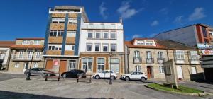 a group of buildings with cars parked in a parking lot at Estudios en Plaza Cabo da Vila centro Muxia in Muxia