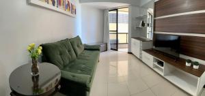 a living room with a green couch and a television at Beira-mar em Pajuçara com excelente localização in Maceió