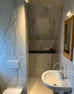 a bathroom with a white sink and a shower at Nuits De Mer in De Haan