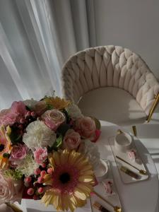 a table with a bouquet of flowers and a chair at Apartament Gold SAUNA&JACUZZI Kołobrzeg in Kołobrzeg