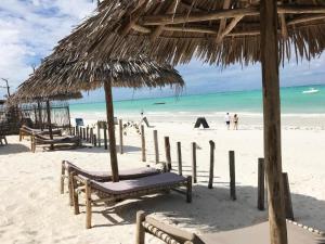 una playa con sillas y una sombrilla de paja y el océano en Duara Beach House, en Paje