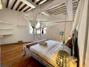 a bedroom with a canopy bed with a chandelier at Duara Beach House in Paje