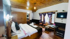a bedroom with a bed and a flat screen tv at Hotel Hilltop At Mall Road Manali With Open Terrace in Manāli