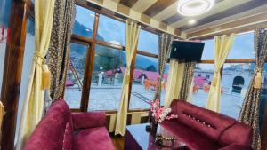 uma sala de estar com uma grande janela e cadeiras roxas em Hotel Hilltop At Mall Road Manali With Open Terrace em Manali