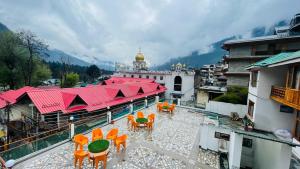 a balcony with orange chairs and tables and a building at Hotel Hilltop At Mall Road Manali With Open Terrace in Manāli