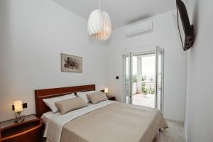 Habitación blanca con cama y lámpara de araña. en villa Ana en Preko