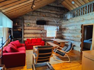 una sala de estar con muebles de color rojo y paredes de madera. en Isokelo Log Apartments en Salla